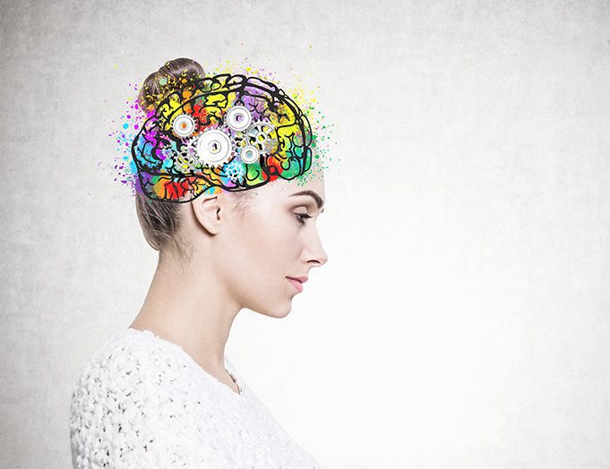 Side view of a calm and beautiful young european woman with a bun wearing a white sweater. Colorful brain sketch with cogs inside her head. Creative thinking concept. Mock up