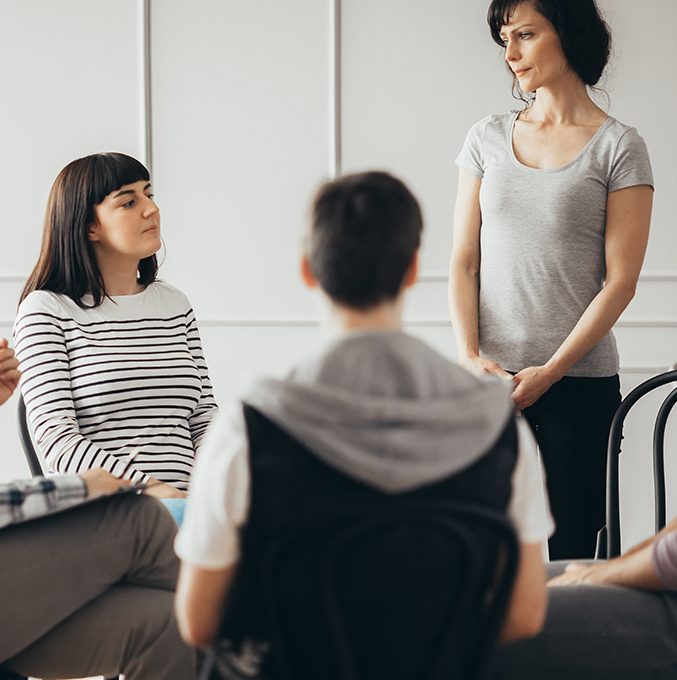 Troubled women listening to pshychologist during support group meeting
