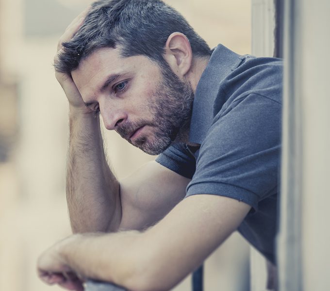 young man alone outside at house balcony terrace looking depressed, destroyed, wasted and sad suffering emotional crisis and depression on urban background